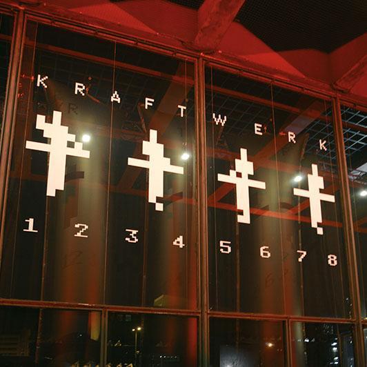 Glasfront mit KRAFTWERK-Logo und Bass-Absorbern im Hintergrund