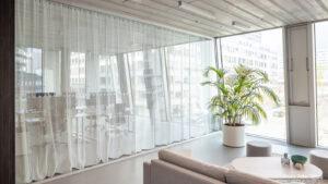 lichtdurchlässige Vorhänge vor Glasfront als Abtrennung zwischen Arbeitsplatz und Ruhezone