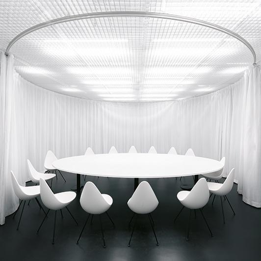 Sala de reuniones con mesa redonda y cortina acústica, todo en blanco