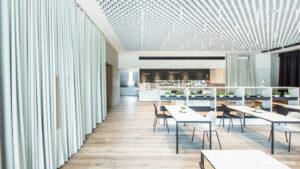 Cafetería acústicamente optimizada mediante cortinas y construcción del techo