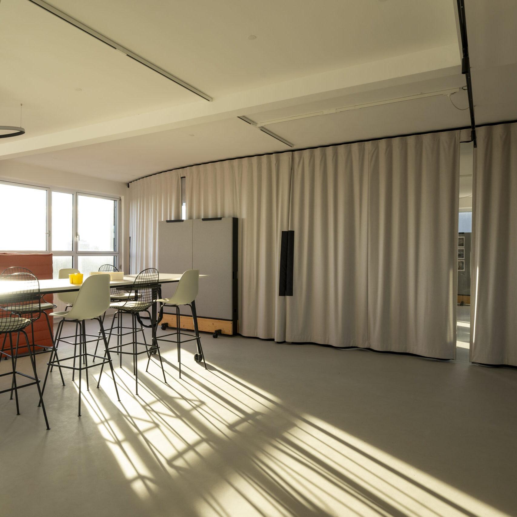 Modern meeting room with high table, chairs and acoustic curtain OFFICE Window in the sunshine